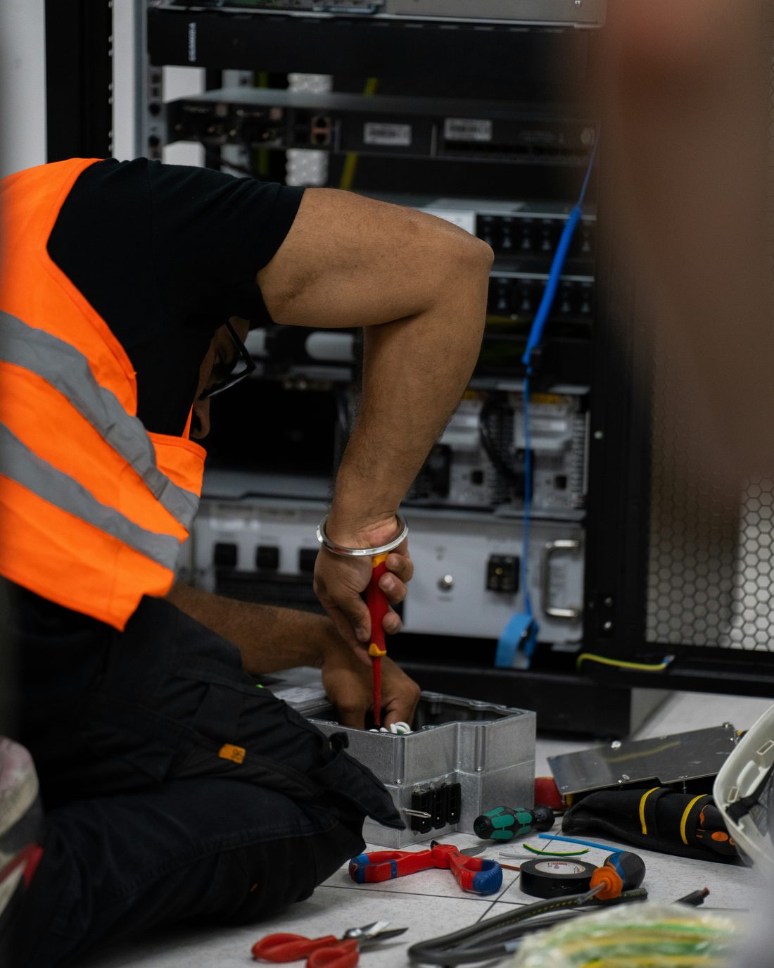 An E&E technician working inside a client's server rack.