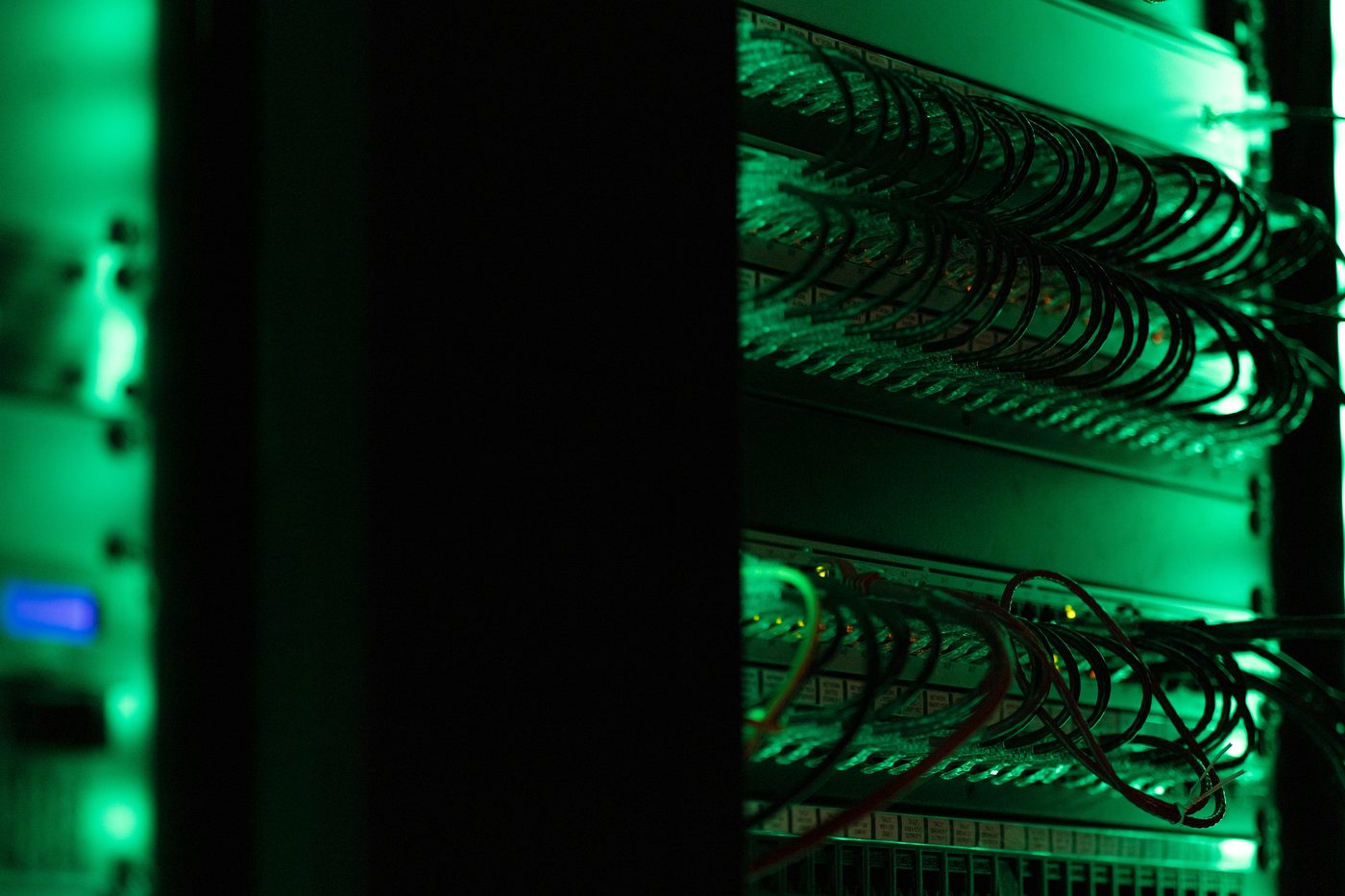 Patch panel in a server rack lit green.